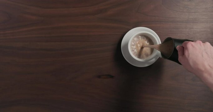 Top View Man Pour Hot Chocolate Into White Cup On Walnut Wood Table