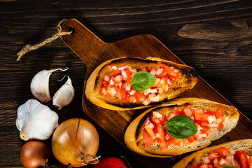 Bruschetta with ingredients on cutting board on wooden background
