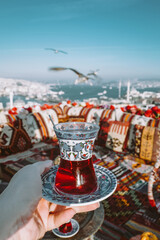 Turkish tea in a female hand against the background of Istanbul city