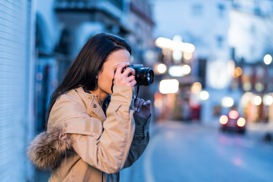 Woman takes pictures on the streets of Granada during blue hour. Granada, Spain