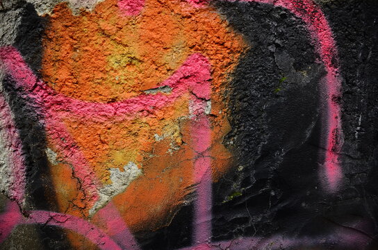 Abstraction in orange and black tones, painted on a concrete wall.