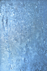 Natural frozen drops of condensation on transparent glass. Beautiful background from a frozen window in winter. Drops texture on the glass