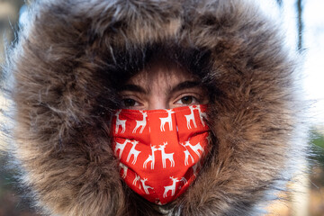 Eine Teenagerin trägt eine selbstgenähte Atemschutz Maske mit Rentier Motiven im Winter