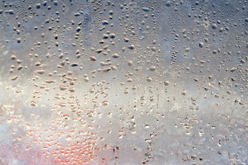 Natural frozen drops of condensation on transparent glass. Beautiful background from a frozen window in winter. Drops texture on the glass