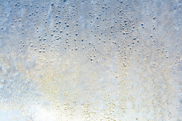 Natural frozen drops of condensation on transparent glass. Beautiful background from a frozen window in winter. Drops texture on the glass