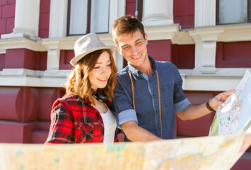 Happy young couple of travelers holding a map in their hands while walking around the city. Travel concept