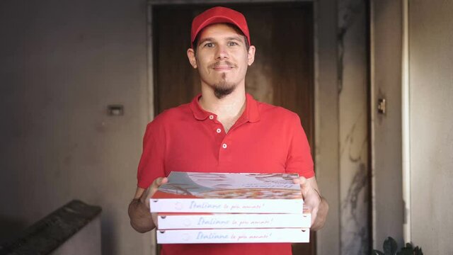 young courier  climbs the stairs of the building to deliver the pizzas
