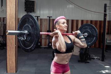 Obraz na płótnie Canvas Athletic woman holding a barbell in modern cross gym. Functional training
