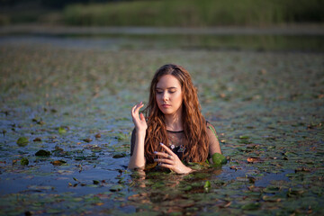 Fototapeta premium beautiful girl bathes in a swamp, a mermaid in a swamp.