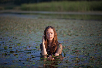 Fototapeta premium beautiful girl bathes in a swamp, a mermaid in a swamp.