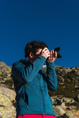 Young boy taking pictures of landscape in the mountain