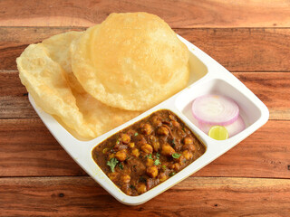 Chole Bhature, spicy Chick Peas curry also known as Chole or Channa Masala is traditional North Indian main course recipe and usually served with fried puri or Bhature, selective focus