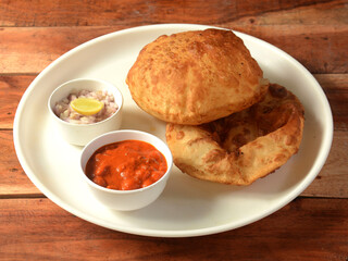 Chole Bhature, spicy Chick Peas curry also known as Chole or Channa Masala is traditional North Indian main course recipe and usually served with fried puri or Bhature, selective focus