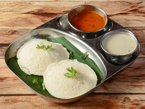 Idli or idly is a healthy Indian, vegetarian, traditional and popular steam cooked rice cakes served with bowls of chutney and sambar as side dishes.selective focus