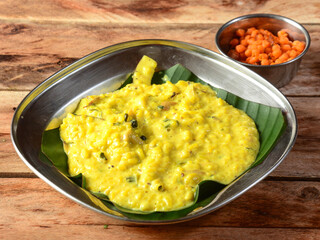 Ven Pongal or khara pongal spicy variety, is a traditional, popular and healthy south Indian vegetarian food made from rice and mung dal, served over a rustic wooden background, selective focus