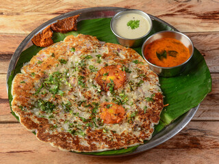 Famous South Indian Food Onion Uttapam or ooththappam is a dosa like dish made by dosa batter, served with coconut chutney and sambar, selective focus