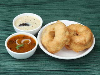 Indian fried snack Medu Vada with sambar and coconut chutney in plate on rustic wooden background, savoury fried snack of Kerala, Tamil Nadu and South India. selective focus