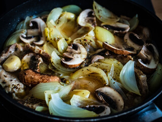 Pork steaks in frying pan with onion, garlic and champignon
