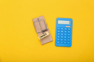 Mousetrap with loan bait and calculator on yellow background. Trap, risks or deception concept