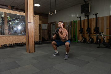 Muscular powerful man exercising with heavy kettlebell in cross fit gym. Functional training with free weights