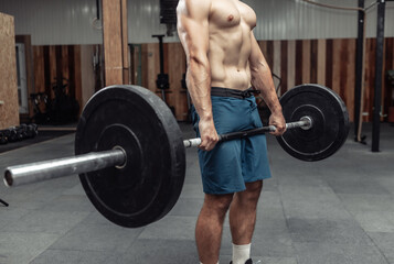 Fototapeta na wymiar Muscular bodybuilding man doing deadlift exercise with a heavy barbell in a modern health club. Bodybuilding and Fitness