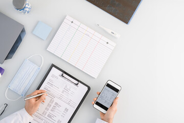 Overview of medical worker hands over history form while scrolling through data