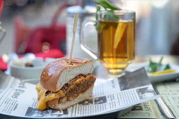 Appetizing hamburger and a glass of tea with lemon in a street cafe