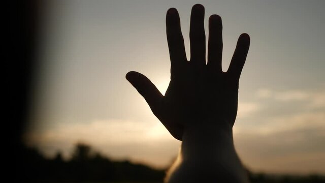 girl stretches out her hand in the sun. faith in god dream a religion concept. hand in the sun close-up silhouette dream sunlight of happiness