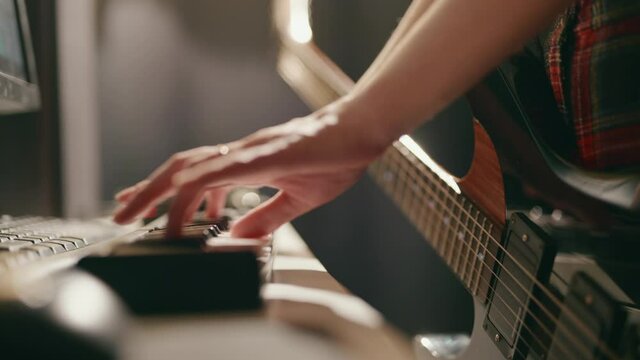 Woman playing guitar and synthesizer creating music. Close up of female hands recording song. Process of creativity.