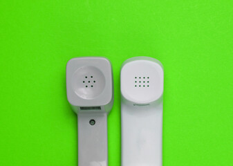 Two retro telephone handsets on green background. Minimalism. Top view