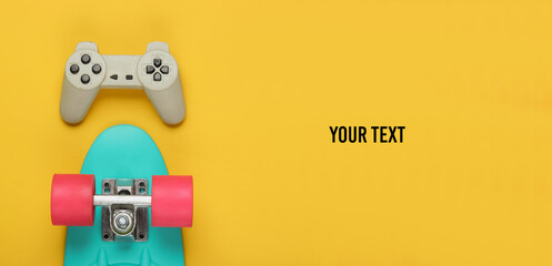 The concept of childhood, entertainment. Cruiser board, gamepad on yellow background with space for your text. Summer fun. Top view