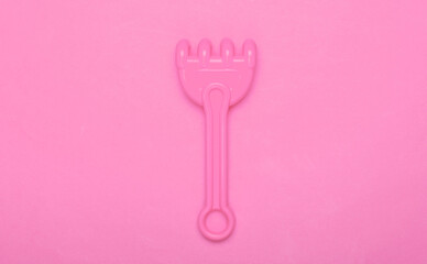 Children's rake for a sandbox or a beach on a pink studio background. Top view