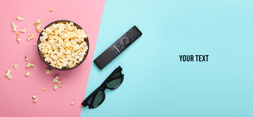 Bowl of popcorn, 3d glasses, tv remote on pink blue pastel background. Copy space. Leisure and...