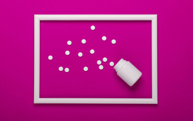 Pills bottle on pink background with white frame. Studio shot. Creative flat lay. Top view. Minimalism