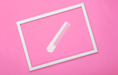 Comb in a white frame on pink background. Top view