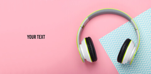 Stylish wireless stereo headphones on pink blue pastel background with copy space. Music lover. Gadgets. Top view.