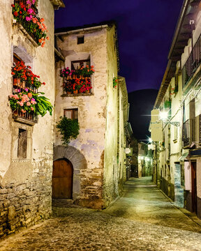 Mountain village street at night. Architecture of stone houses, balconies with flowers and illuminated alleys. Torla Ordesa.
