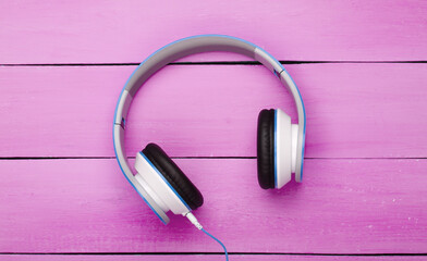 Wired stereo headphones on pink wooden boards. Music lover. Gadgets. Top view.