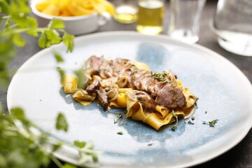 Tagliatelle pasta with sirloin and mushroom sauce.
Food, an appetizing dish on a plate. A proposal for an application. Culinary photography.