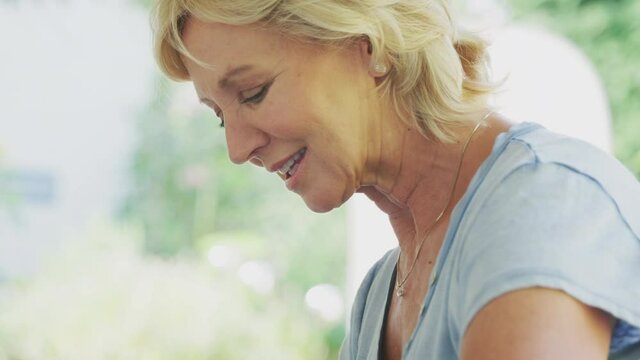 Close up of senior woman planting plants into wooden garden planter at home - shot in slow motion