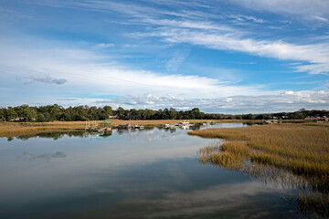 Fototapeta na wymiar View of Shem Creek with marshland on both sides and reflections of the sky in the water.