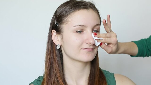 Young woman cleans her face before makeup with a cotton pad making makeup. Making mua. Make-up artist in studio teach a beautiful girl to clean face in right way along massage lines. Face care hygiene