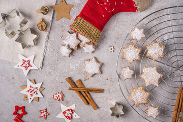 Zimtsterne Gebäck in einem Stoffstiefel auf einem Küchentisch mit Zimtstangen, Ausstechform und Deko, draufsicht
