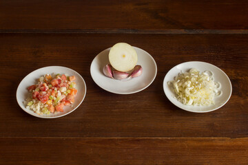Three white plates on a wooden table filled with sauteed vegetables, garlic, and leek. Natural food ingredients and vegetables. Preparation of cooked dishes.