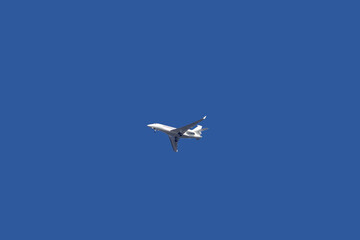 A passenger jet with its landing gear out approaching an airport under blue sky 