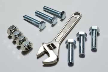 screw-nut of different sizes, bolts and adjustable spanner. White background.