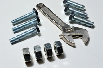 screw-nut of different sizes, bolts and adjustable spanner. White background.