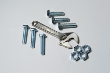 screw-nut of different sizes, bolts and adjustable spanner. White background.