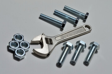 screw-nut of different sizes, bolts and adjustable spanner. White background.