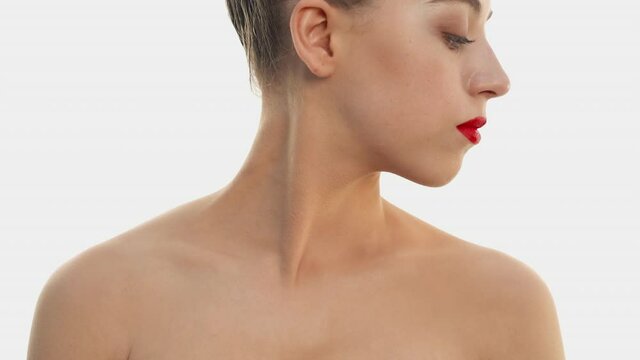 Young woman with virtually no makeup. Foundation and powder are applied on the face. Blond girl in profile runs her fingers along her neck and collarbone. Concept of cosmetics, natural beauty.